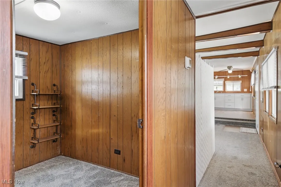 Hallway featuring carpet and wooden walls