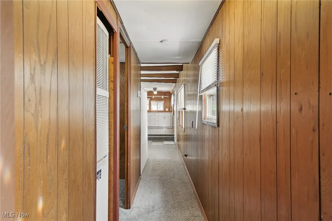 Hallway featuring carpet floors and wood walls