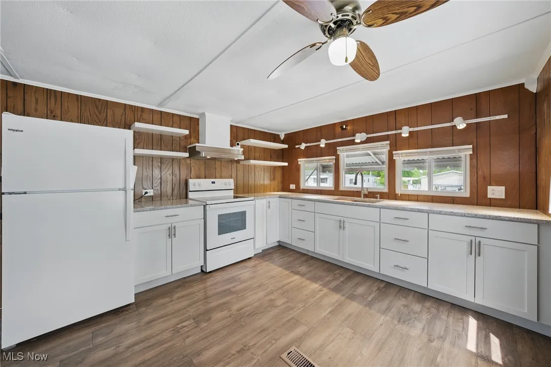 Kitchen featuring white appliances, a sink, open shelves, a ceiling fan, and light countertops