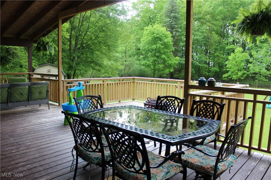 Deck with outdoor dining space and a wooded view