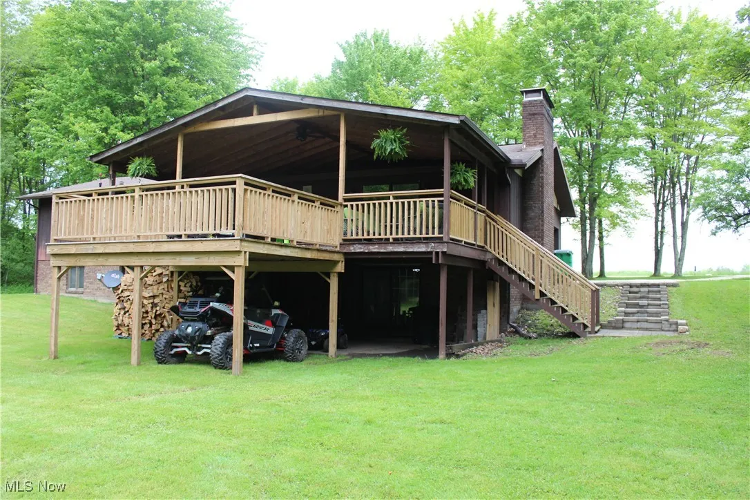 Back of house featuring a chimney, a yard, a deck, and stairway