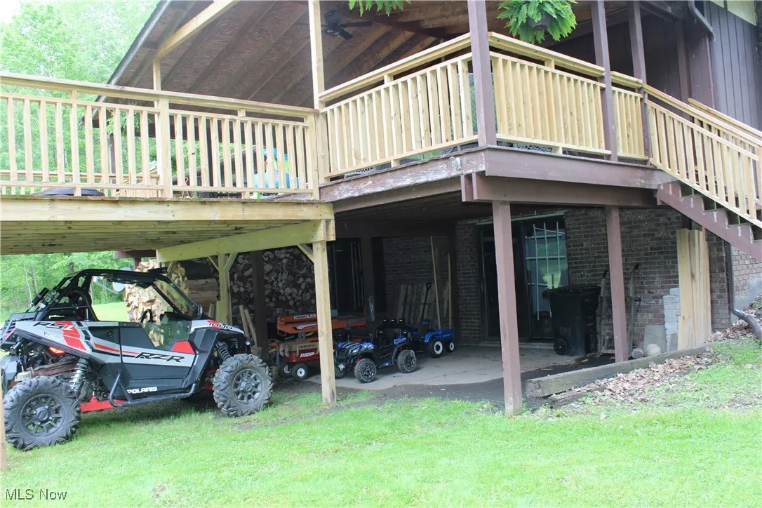 View of side of home featuring brick siding, a carport, a deck, a yard, and stairs