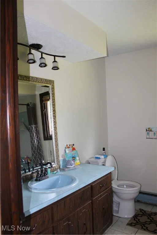 Full bath featuring vanity, toilet, a baseboard radiator, and tile patterned flooring