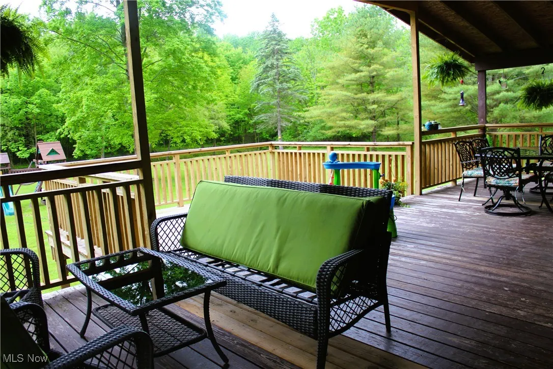 Wooden terrace featuring outdoor dining space and a forest view