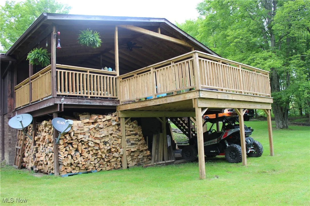 View of property exterior with a yard, a ceiling fan, and a wooden deck