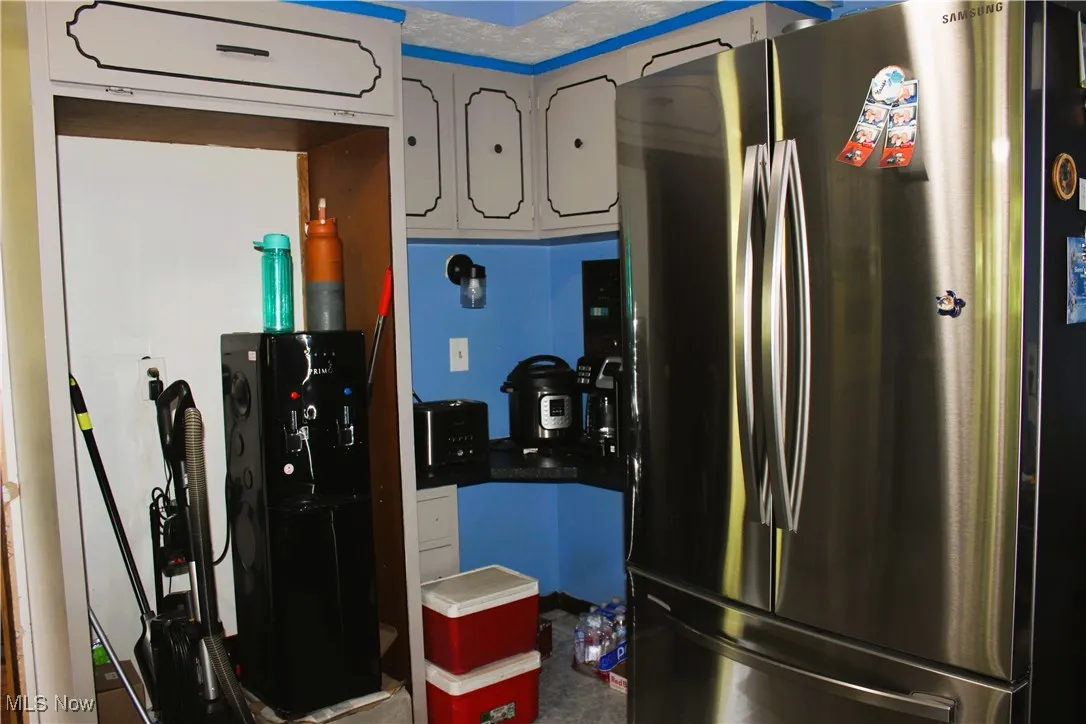 Kitchen featuring freestanding refrigerator and white cabinetry