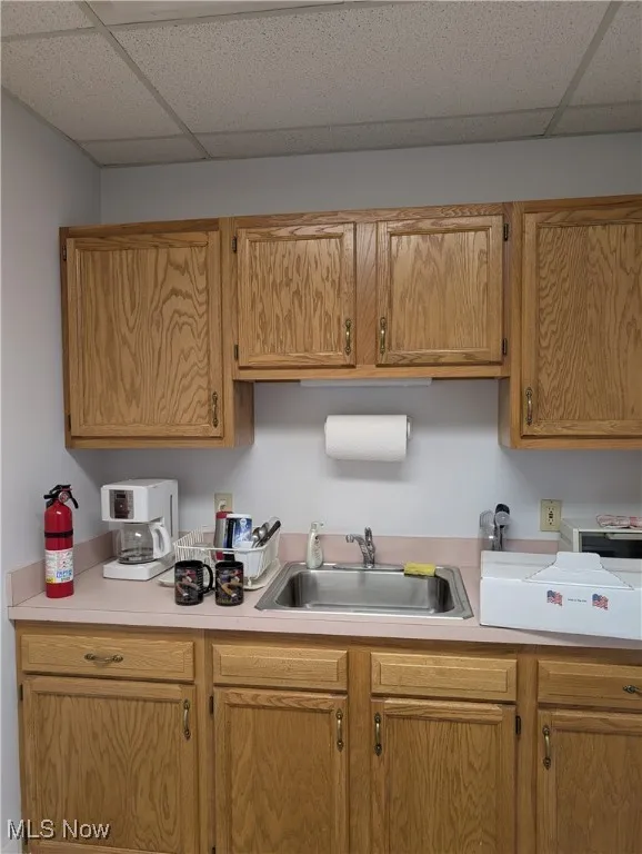 Kitchen with a paneled ceiling, a sink, and light countertops
