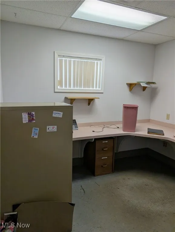 Unfurnished office featuring a drop ceiling and built in desk