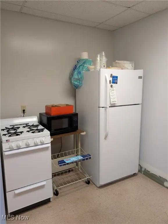 Kitchen featuring white appliances, a drop ceiling, and light​​‌​​​​‌​​‌‌​‌‌​​​‌‌​‌​‌​‌​​​‌​​ floors