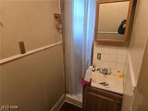 Full bath featuring vanity, curtained shower, and backsplash