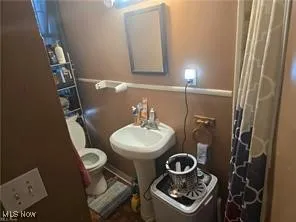 Full bathroom featuring toilet and a shower with shower curtain