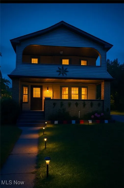 View of front of house featuring a porch, a balcony, and a front lawn