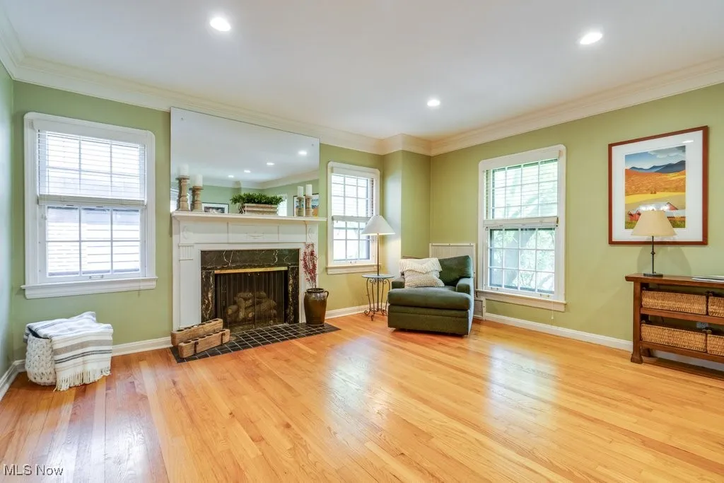 Living area featuring wood finished floors, a high end fireplace, baseboards, ornamental molding, and recessed lighting