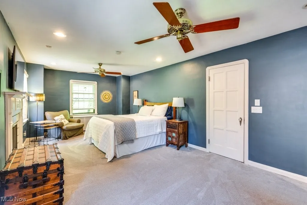 Carpeted bedroom featuring baseboards, recessed lighting, a ceiling fan, and a fireplace