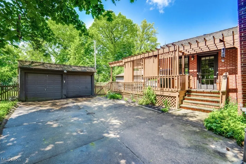 View of front of home with a garage, a deck, brick siding, and fence