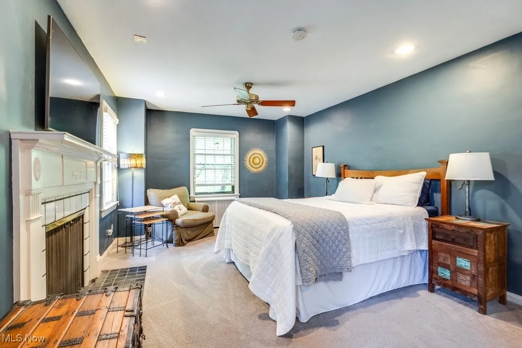 Bedroom with light carpet, a fireplace with flush hearth, baseboards, recessed lighting, and ceiling fan
