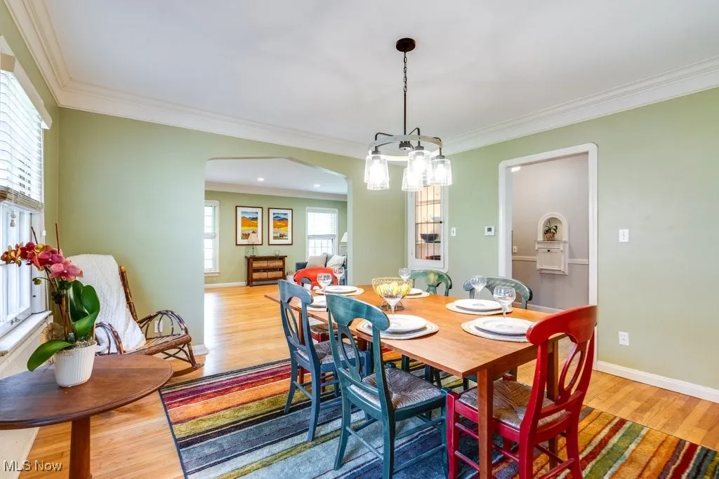 Dining area featuring arched walkways, wood finished floors, crown molding, and baseboards