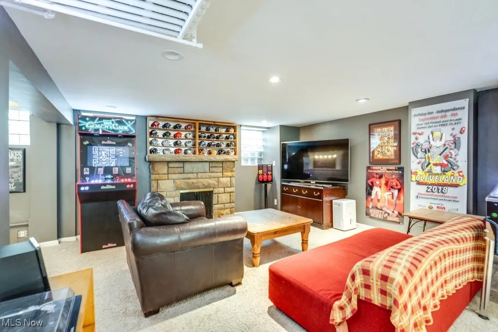 Living area with a stone fireplace, recessed lighting, and carpet floors