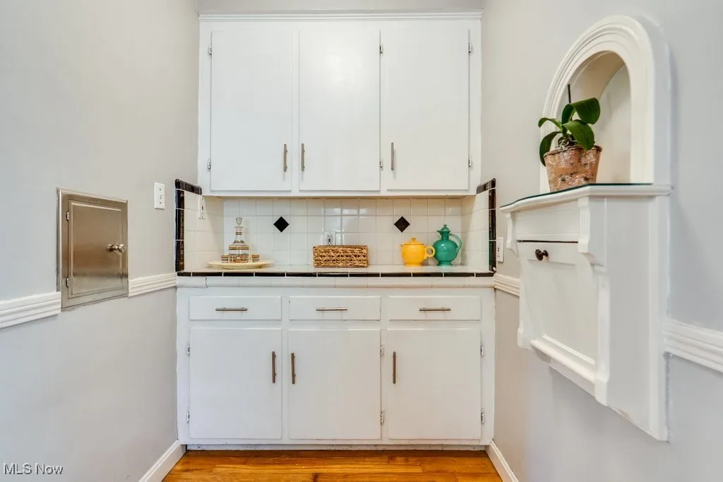 Kitchen featuring tile countertops, tasteful backsplash, white cabinets, and light wood-style flooring