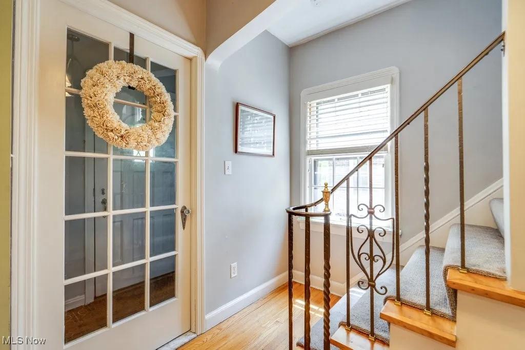 Foyer featuring wood floors, stairs, and baseboards