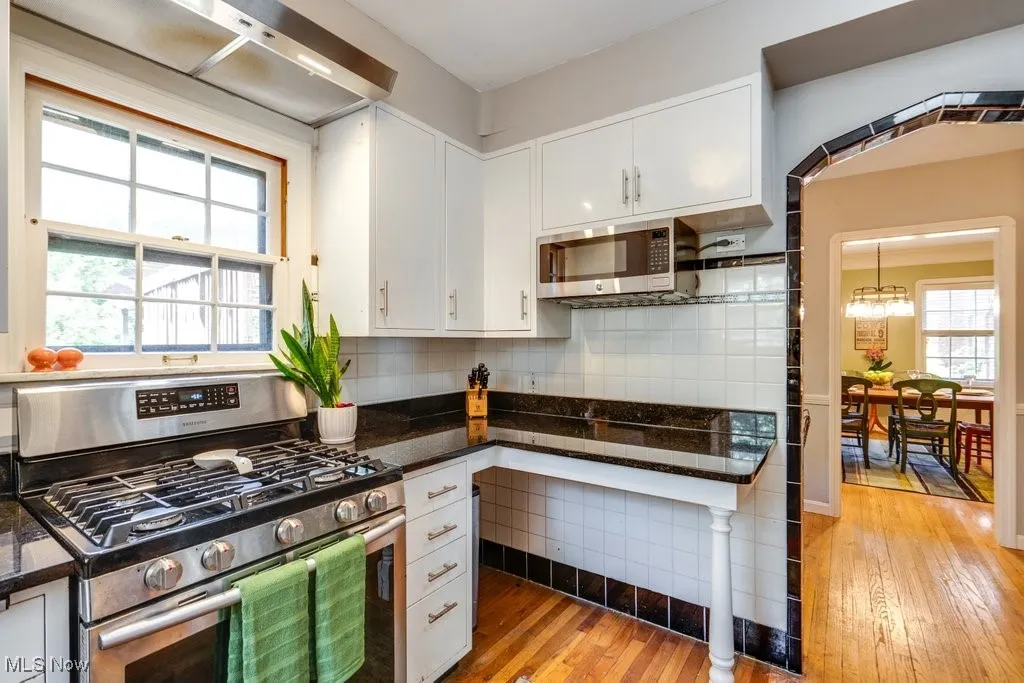 Kitchen with stainless steel appliances, light wood-style flooring, white cabinets, tasteful backsplash, and a chandelier
