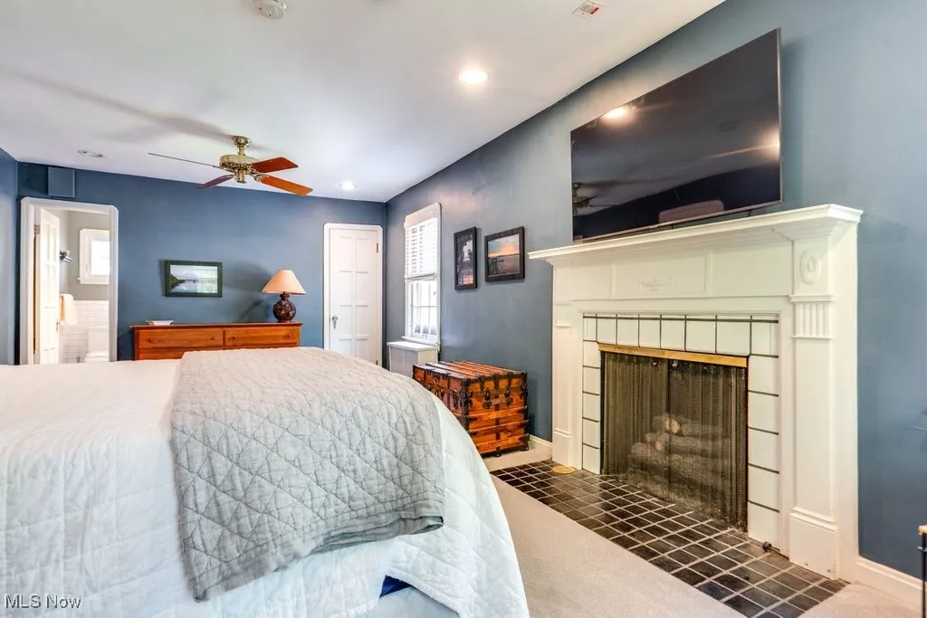Bedroom with a tiled fireplace, recessed lighting, baseboards, connected bathroom, and a ceiling fan