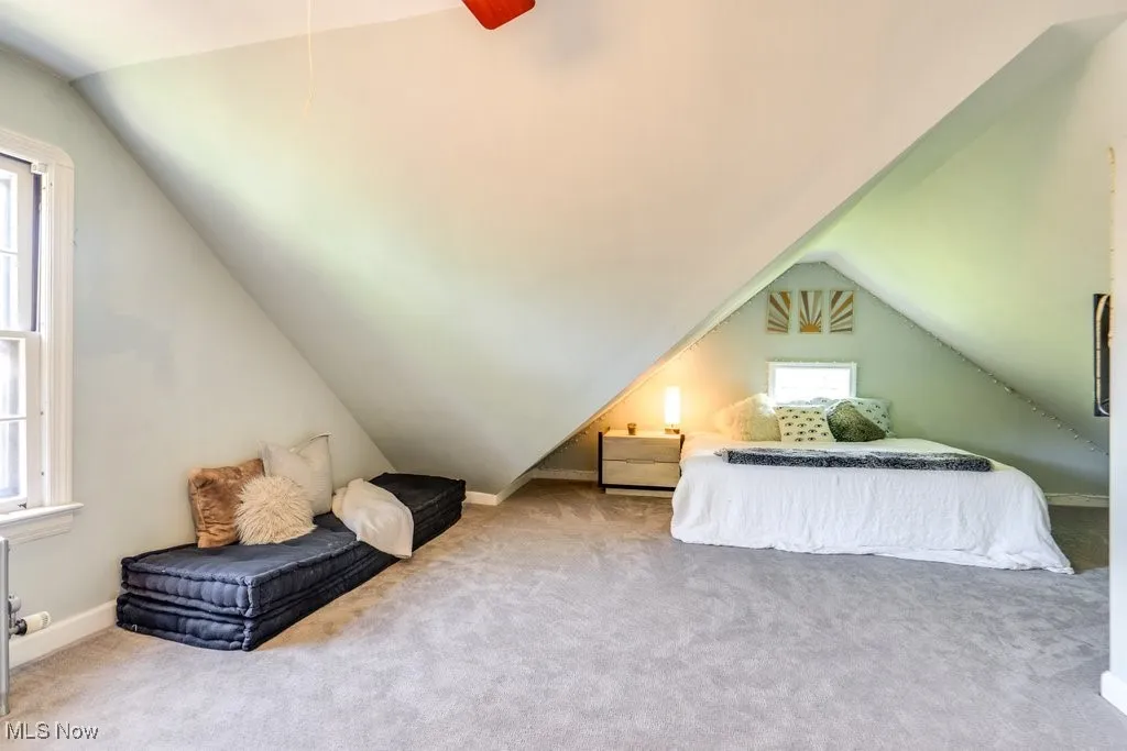 Carpeted bedroom with vaulted ceiling, baseboards, and a ceiling fan