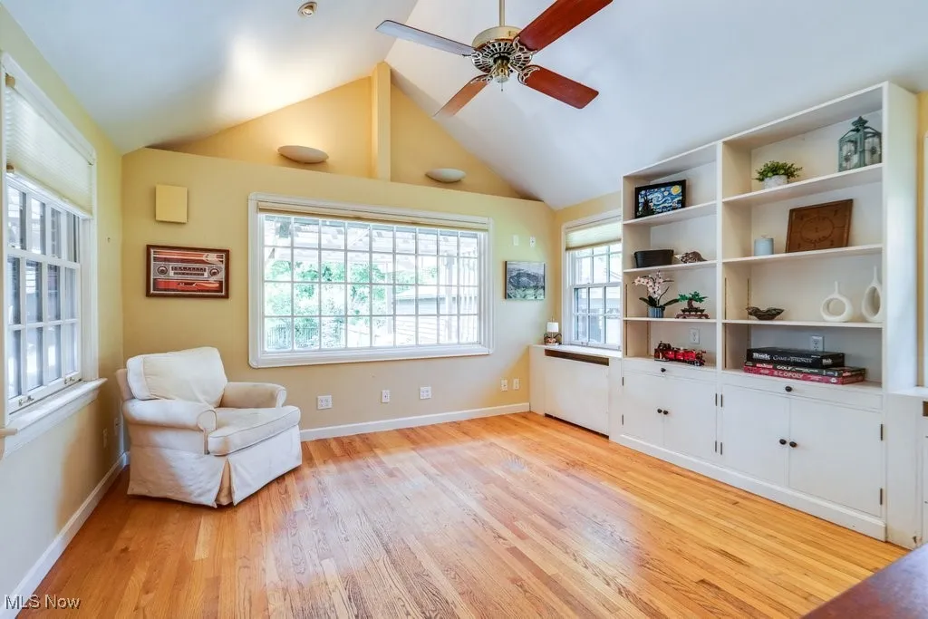 Sitting room featuring light wood-style floors, a ceiling fan, vaulted ceiling, and baseboards