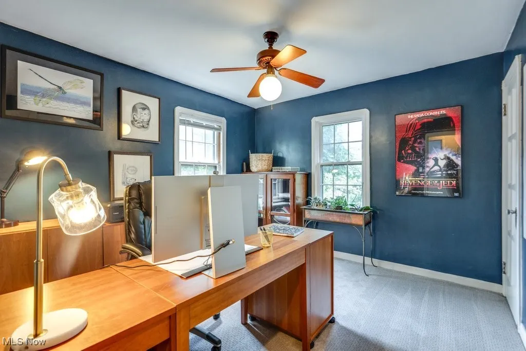 Carpeted office featuring a ceiling fan and baseboards