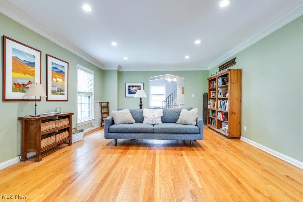 Living area featuring plenty of natural light, arched walkways, wood finished floors, crown molding, and baseboards