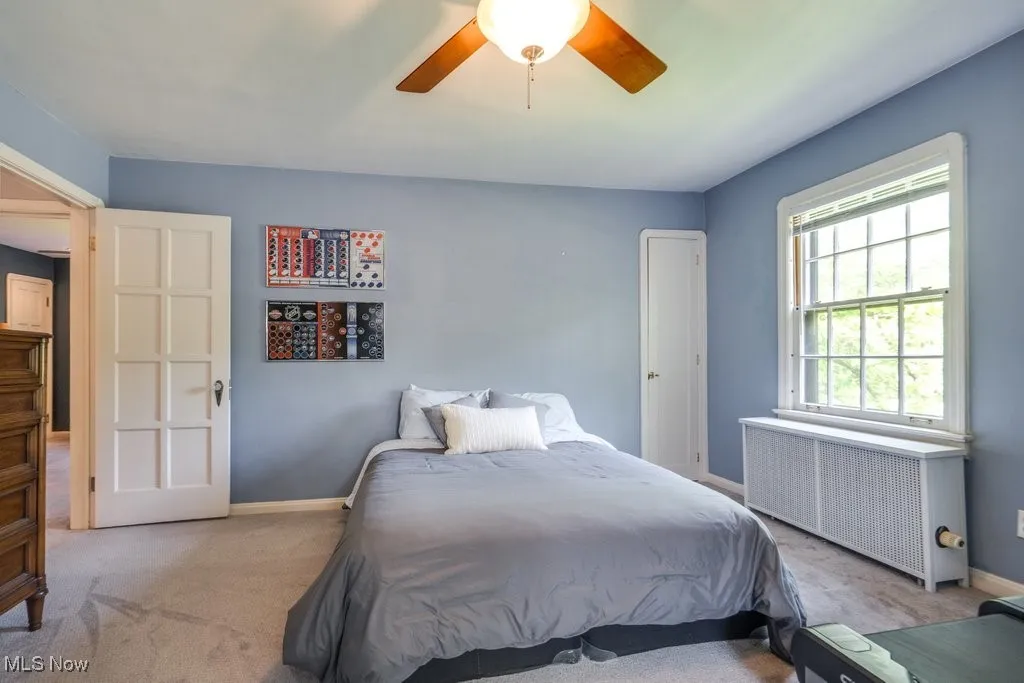 Bedroom with radiator heating unit, carpet floors, baseboards, and a ceiling fan