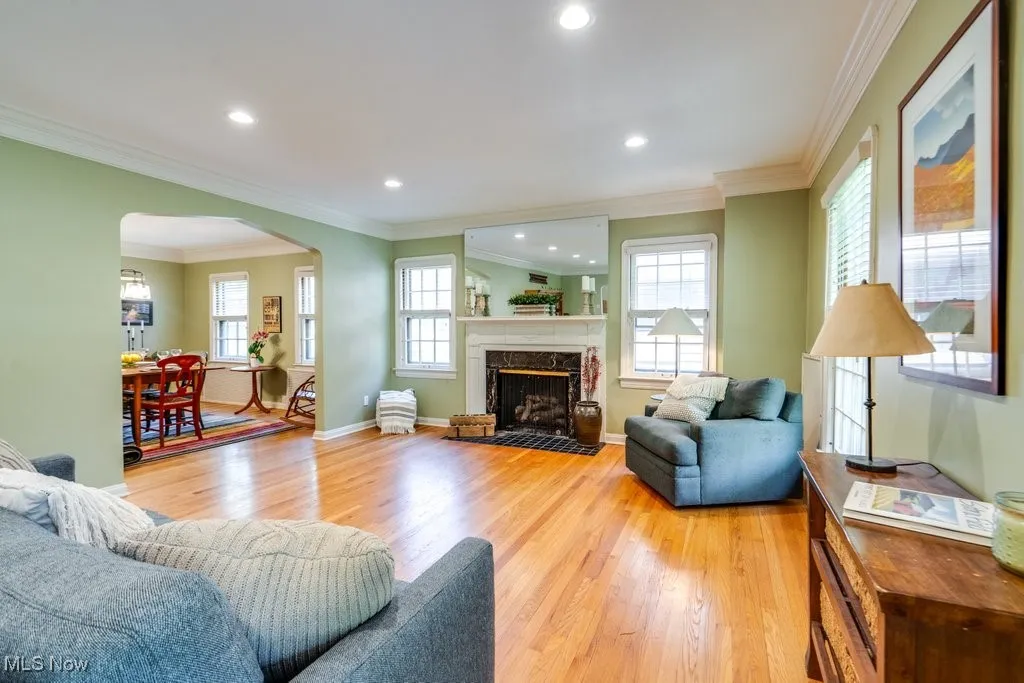 Living room with arched walkways, light wood-style flooring, plenty of natural light, recessed lighting, and ornamental molding