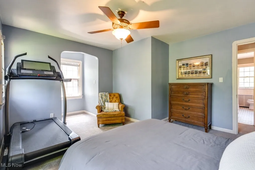 Bedroom featuring carpet, baseboards, arched walkways, and ceiling fan