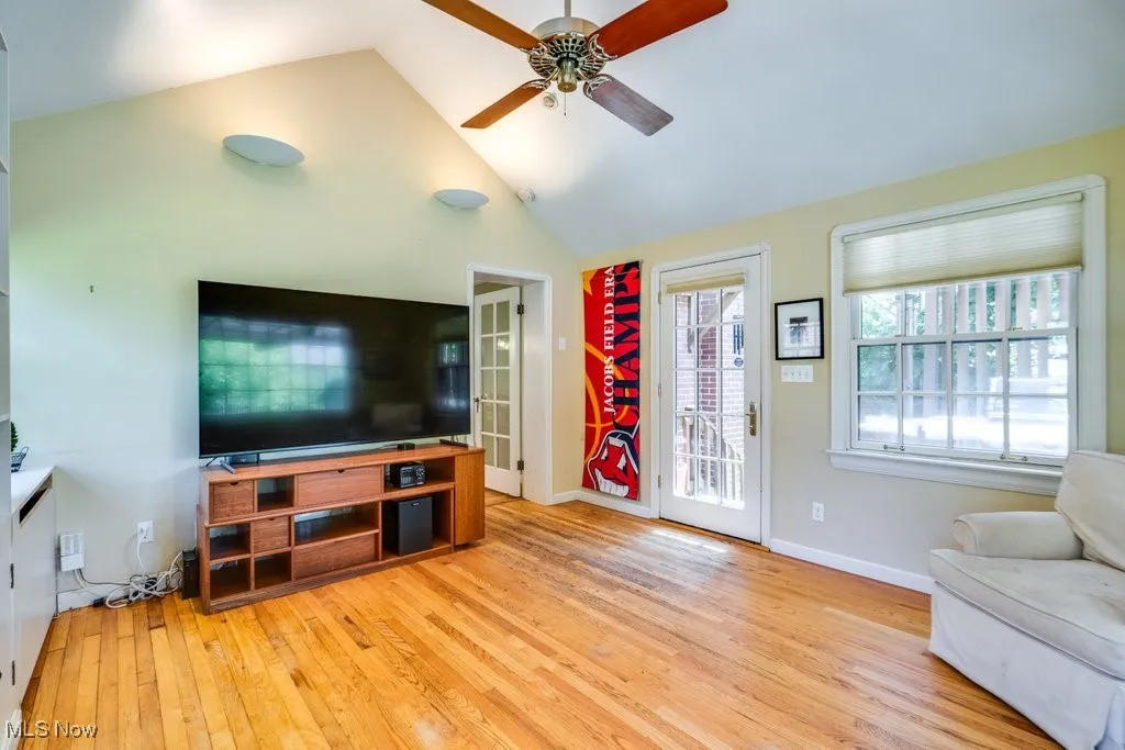 Living room with wood finished floors, a ceiling fan, baseboards, and high vaulted ceiling