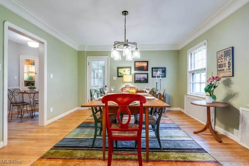 Dining space featuring light wood finished floors, a chandelier, ornamental molding, and baseboards