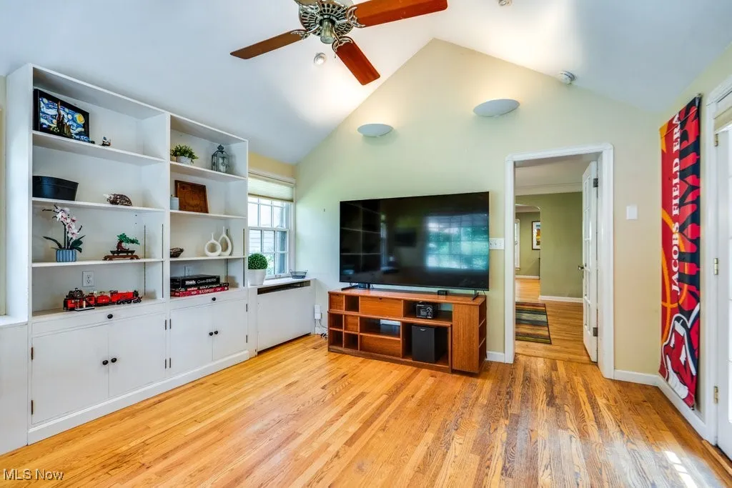 Living room featuring a ceiling fan, light wood-type flooring, and lofted ceiling