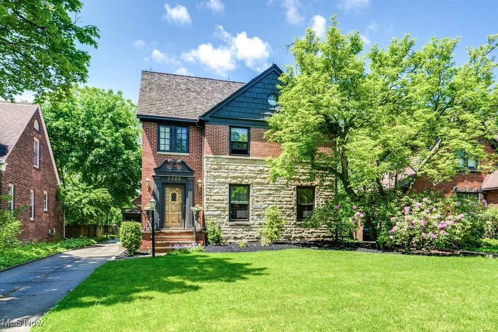 Tudor-style house featuring a front lawn, stone siding, and brick siding