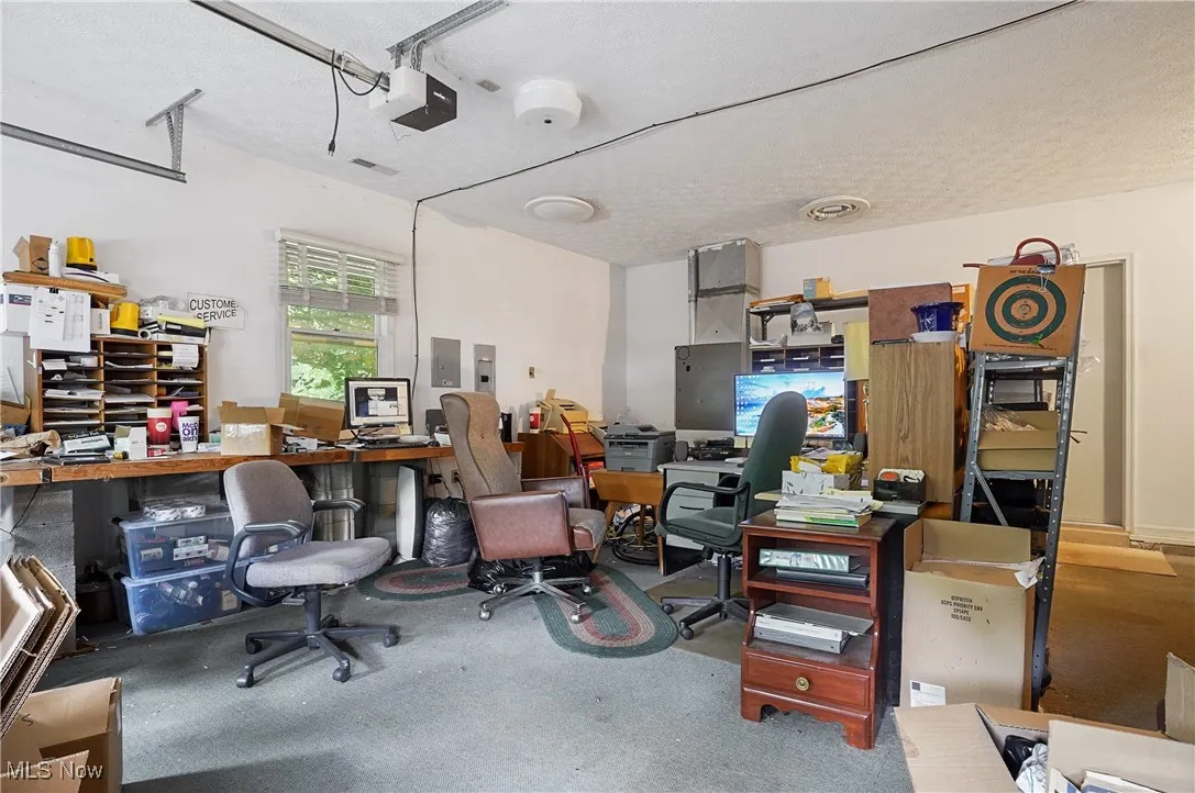 Carpeted home office with electric panel and a textured ceiling