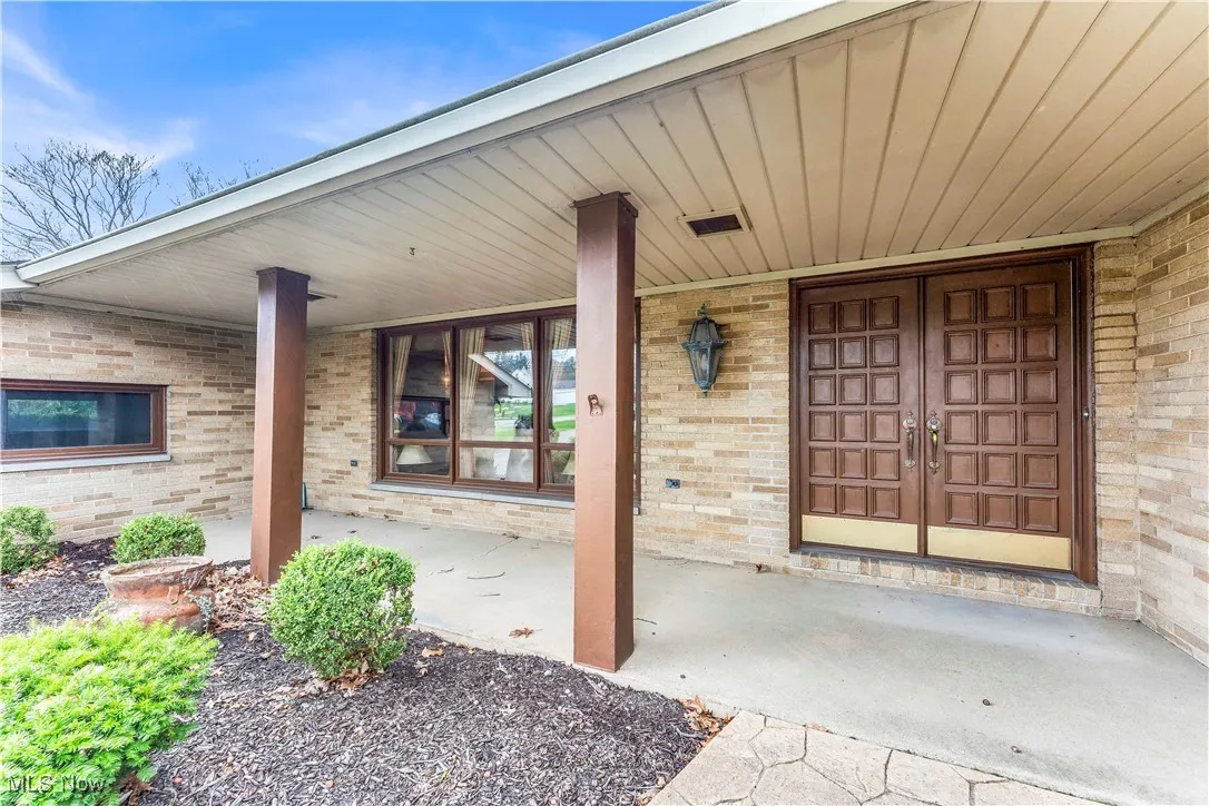 Entrance to property with brick siding and a porch