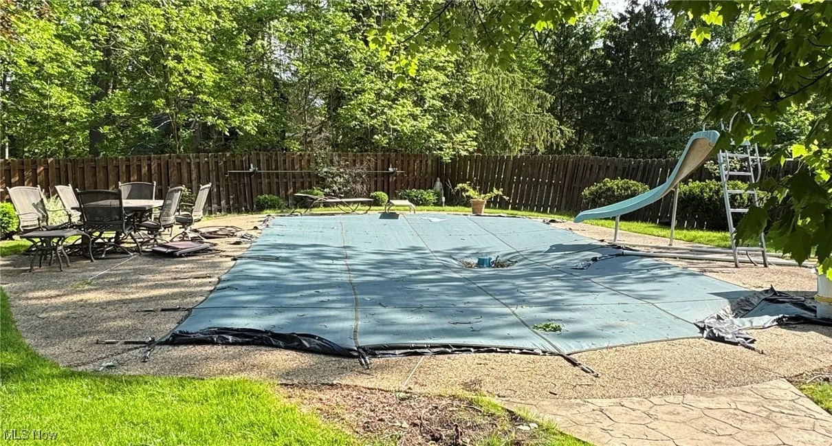 View of pool featuring a fenced backyard, a water slide, and a patio area