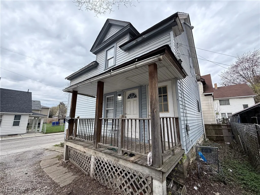 Shotgun-style home with covered porch and fence