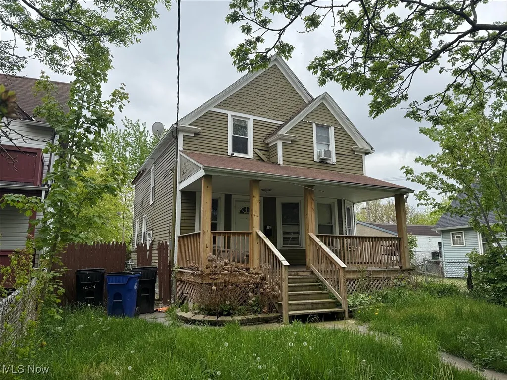 View of front of property featuring covered porch, fence, and cooling unit