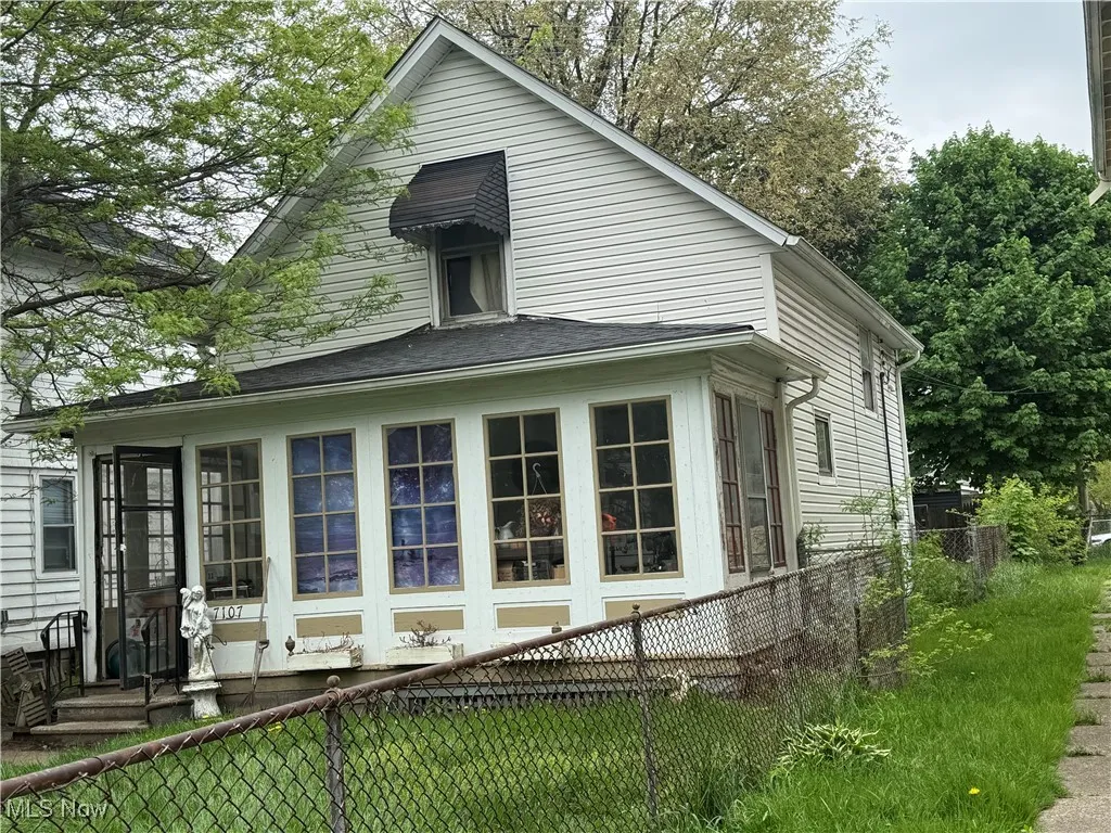 View of side of home featuring a fenced backyard and a sunroom