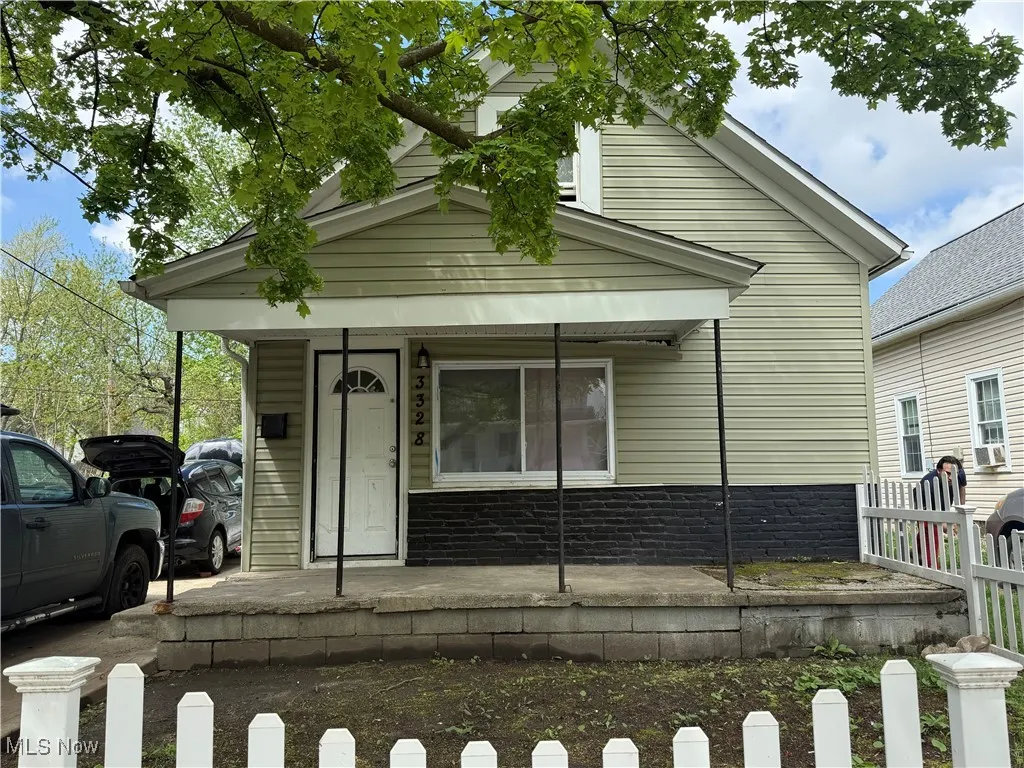 Shotgun-style home featuring covered porch and fence