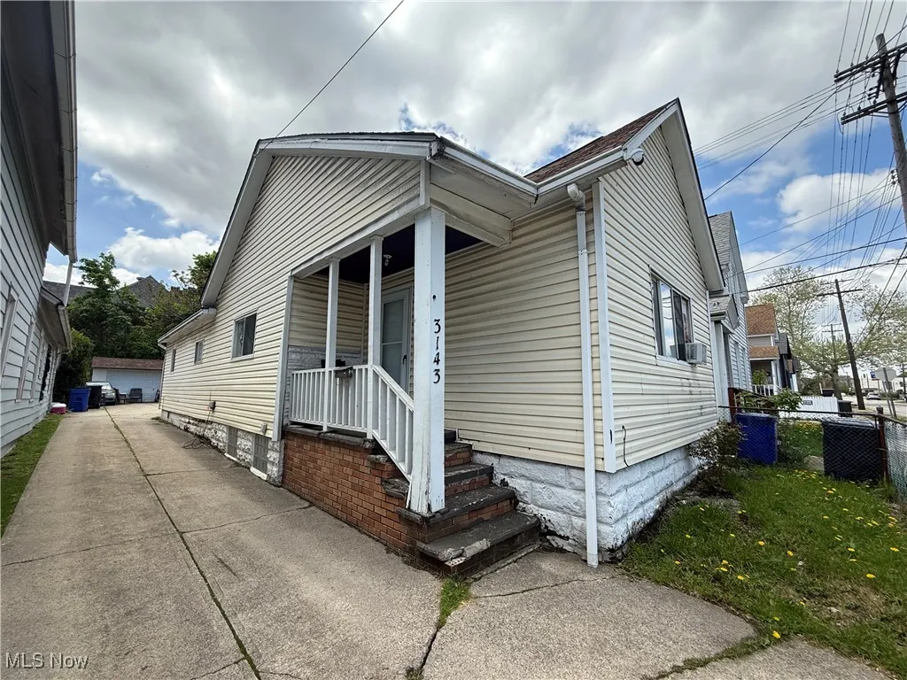 View of property exterior with fence, covered porch, and cooling unit