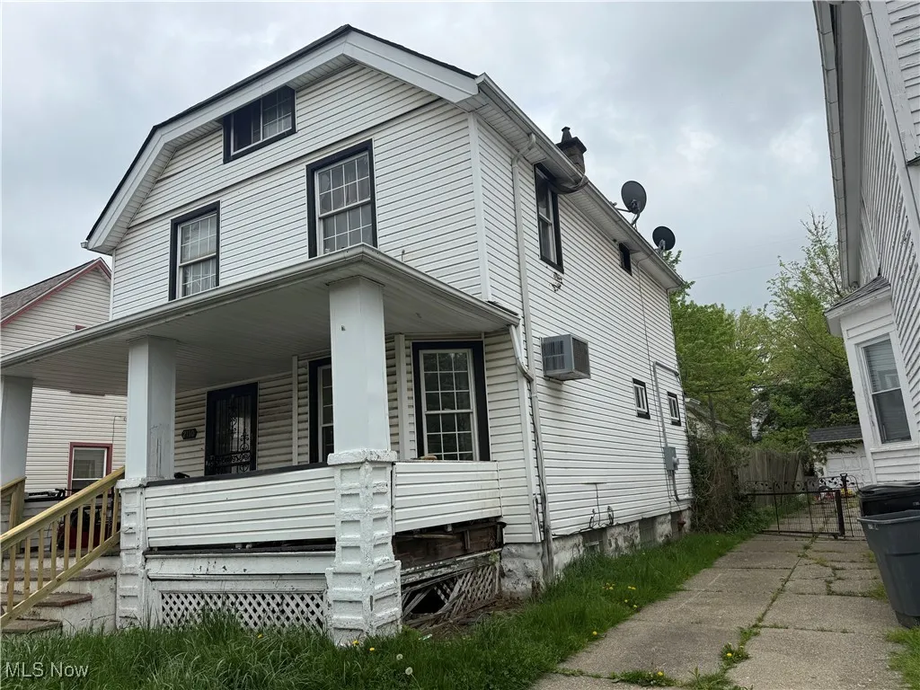 View of front of property featuring covered porch, a wall mounted AC, and a chimney
