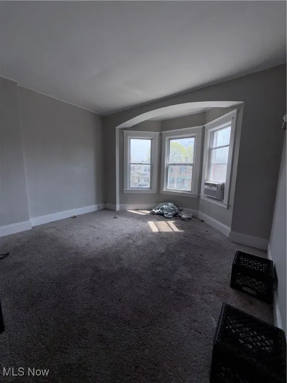 Carpeted empty room featuring baseboards and cooling unit