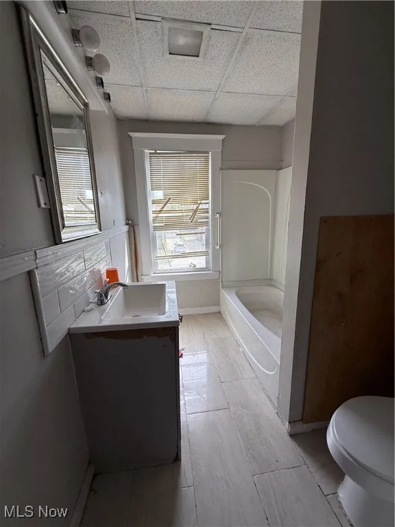 Full bath with vanity, shower / bathtub combination, toilet, and a drop ceiling