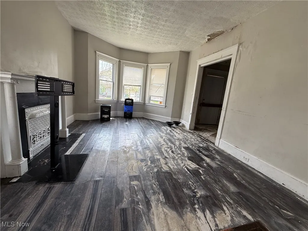Unfurnished living room with dark wood finished floors, baseboards, and a textured ceiling