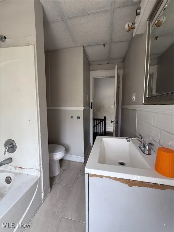 Bathroom with a paneled ceiling, toilet, and vanity
